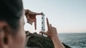 A person framing a lighthouse with their hands, symbolising focus, clarity and direction—reflecting the idea of choosing a personal intent word for the year.