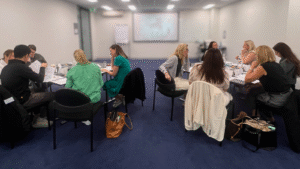 A leadership group seated in small breakout circles, engaging in structured reflection and discussion during a year-end leadership development workshop.