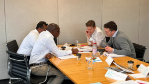 A leadership team seated around a table reviewing documents and discussing decisions during a focused working session.