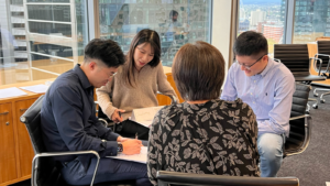 A small group of professionals seated in discussion, reviewing notes together during a facilitated workplace conversation.