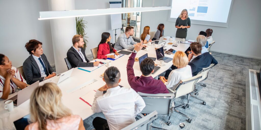 Senior leader presenting to a diverse executive team seated around a conference table during a strategy meeting