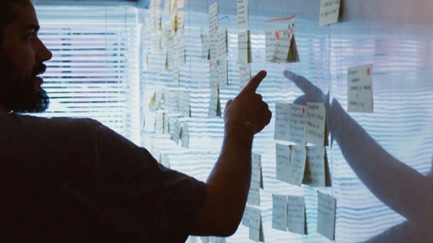 Leader reviewing strategy notes on a wall filled with sticky notes during a planning session